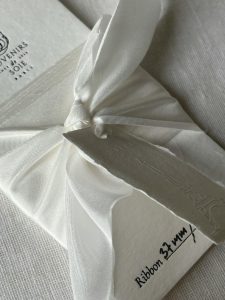White ribbon and material sample kit for a white winter wedding invitation design