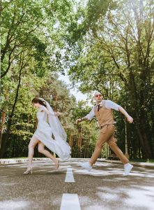 Bride and groom crossing the street in a rush